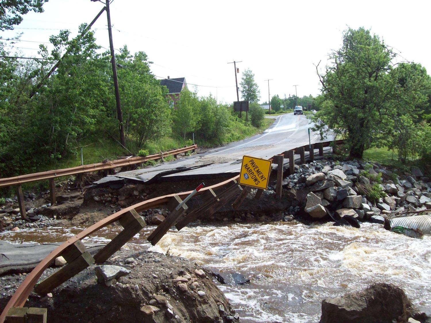 Broken road with flood waters running through