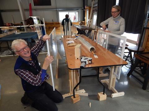 Two people with partially built windows next to a wooden table