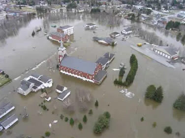 Buildings surrounded by flooding with trees interspersed between them.